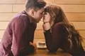 The attractive couple kissing at the cafe table Photo