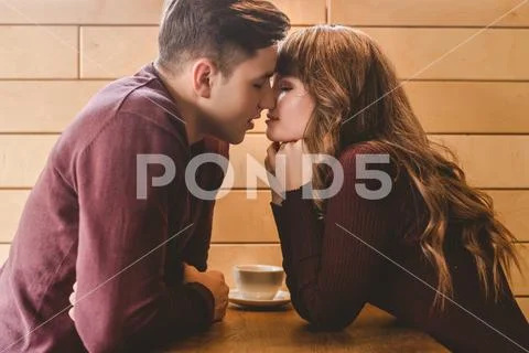 The attractive couple kissing at the cafe table Stock Photos