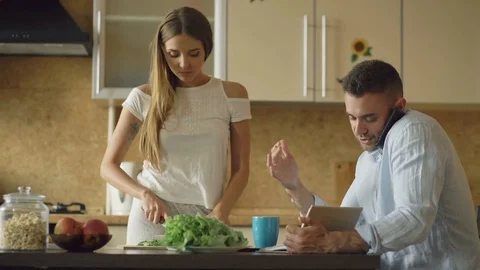 Attractive couple in the kitchen early morning. Beautiful girl cooking breakfast Stock Footage