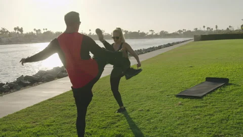 Attractive couple performs leg exercise fitness workout together at Marina park Stock Footage 136020488