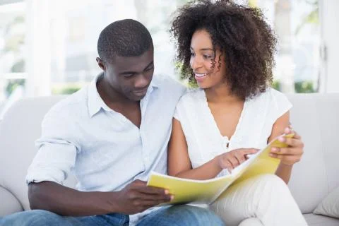 Attractive couple relaxing on couch together looking at photo album Stock Photos