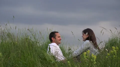 Attractive couple resting on spring meadow close sky, talking, dreaming 4K Video stock 46206347
