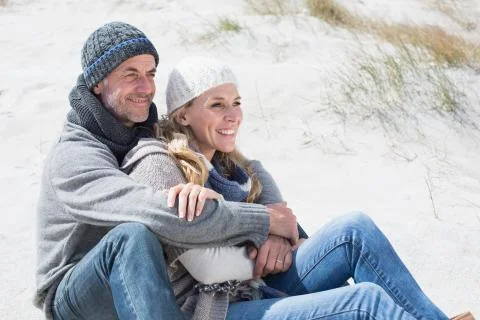 Attractive couple smiling on the beach in warm clothing Stock Photos