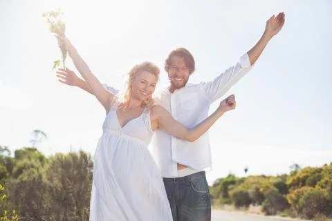 Attractive couple standing with arms raised by the road Stock Photos