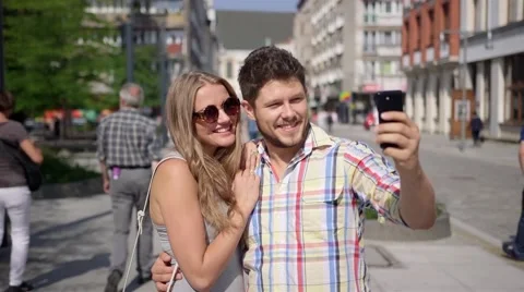 Attractive couple taking self-portrait with smartphone in a city street Stock Footage 41479930