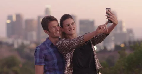 Attractive couple taking selfies in front of Los Angeles skyline at dusk 4K Stock Footage 68185275