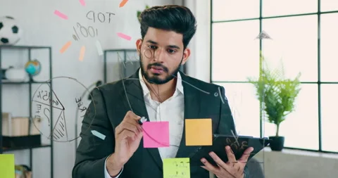 Attractive creative experienced bearded worker writing notes on glass wall and Stock Footage 157935235