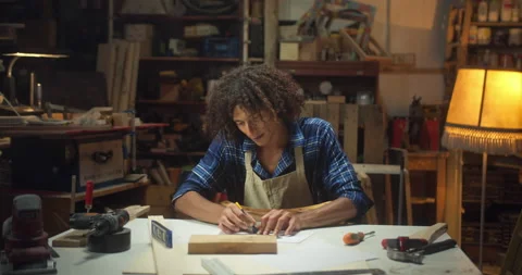 Attractive curly young master joiner drawing furniture project using ruler in Stock Footage 140628098