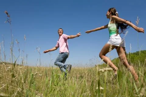 Attractive dates having fun while running down green field during weekend Stock Photos
