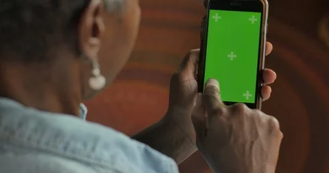 Attractive elderly black woman swiping her finger on a green screen mobile phone Stock Footage