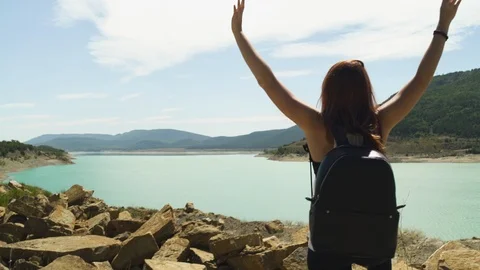 Attractive explorer female standing hands up, hiking at beautiful blue turquoise 動画素材 119347327