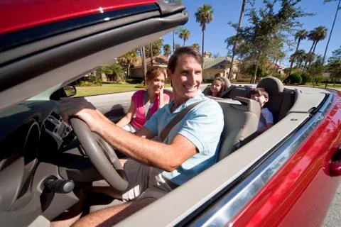 Attractive family driving red convertible car Stock Photos