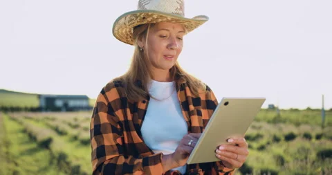 Attractive farmer woman in hat using digital tablet computer in agricultural Stock Footage 252906405