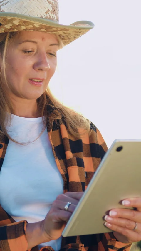 Attractive farmer woman in hat using digital tablet computer in agricultural rip Stockbeeldmateriaal 334453652