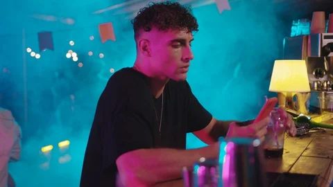 Attractive fashion boy using smartphone social media drinking a cocktail sitting Stock Footage 115366397