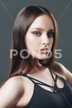 Attractive fashion model posing at studio in black top on a gray background. Stock-Fotos