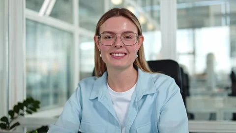Attractive female adjusting glasses while looking at camera in private office Video stock 276426543