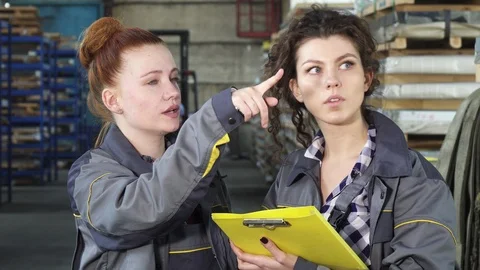 Attractive female engineer talking to her colleague at the factory warehouse Stock Footage 89040623