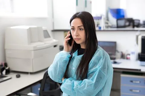 Attractive female lab worker using mobile phone at her workplace in the Stock Photos