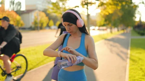 Attractive female model setting her smartwatch before fitness training outdoors. 動画素材 342599582