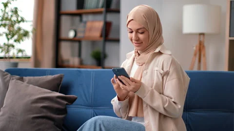 Attractive female muslim using smartphone searching online information sitting Stock Footage 196791253
