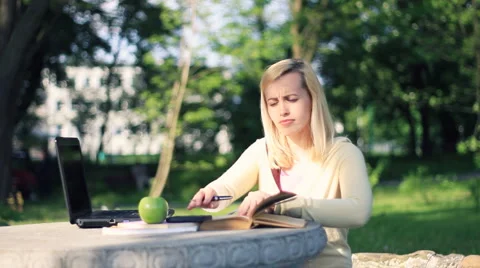 Attractive female student doing homework, outdoors, dolly shot HD Stock Footage