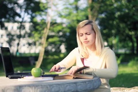 Attractive female student doing homework, outdoors, dolly shot NTSC Stock Footage 5297765