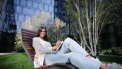 Attractive freelancer working on nature sitting with notepad Stock Footage 262142604