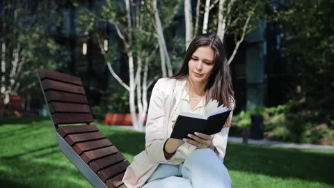 Attractive freelancer working on nature sitting with notepad. Green spring park Stock Footage 262143191