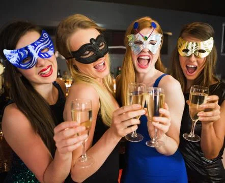 Attractive friends with masks on holding champagne glasses Stock Photos