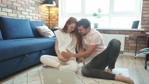 Attractive future parents sit on the floor with laptop Stock Footage 137694930