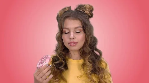 Attractive girl with a beautiful styling eats a donut and enjoys the taste Video stock 104988111