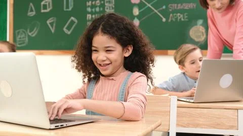 Attractive girl coding prompt while looking at camera at STEM class. Pedagogy. Stock Photos