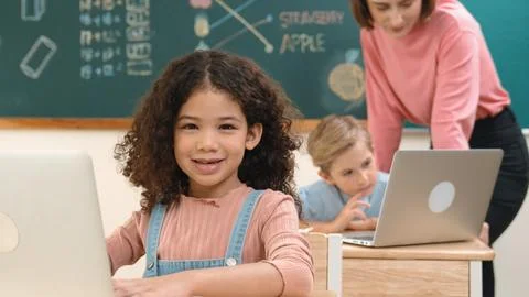 Attractive girl coding prompt while looking at camera at STEM class. Pedagogy. Stock Photos