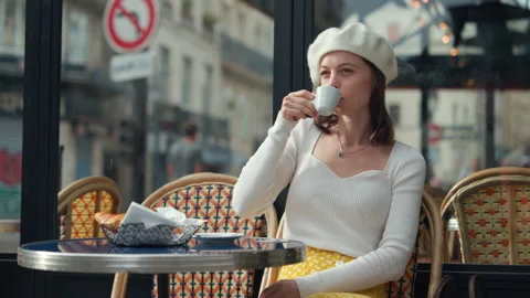 Attractive girl drinking coffee at a table in an outdoor cafe Stock Footage 233268224