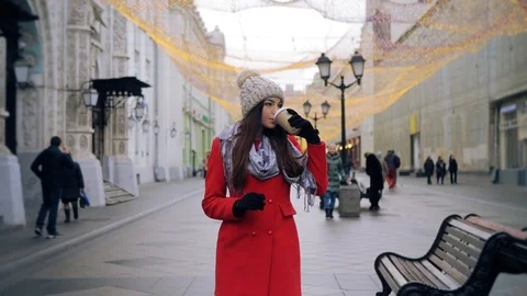 Attractive girl is drinking coffee while walking down the street outdoors. Stock Footage 99239004