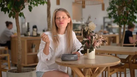 Attractive girl drinking tea with cake in cafe Stock Footage 214337740