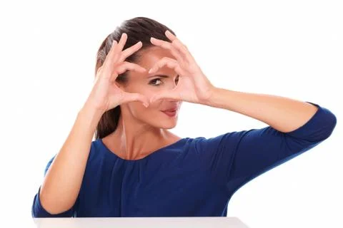 Attractive girl looking at you through a love sign made with hands , front vi Stock Photos