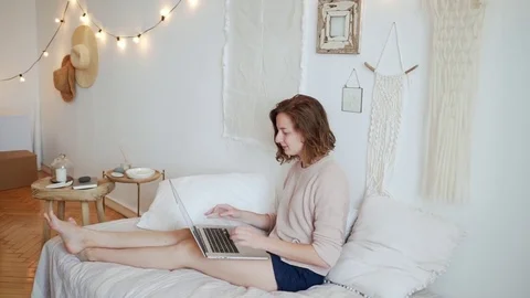 Attractive girl lying on sofa using laptop and smiling Stock Footage 78005243