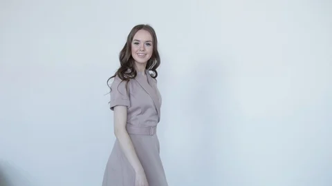 Attractive girl model posing smiling in grey dress on grey background .Slow mo Stock Footage 107826864