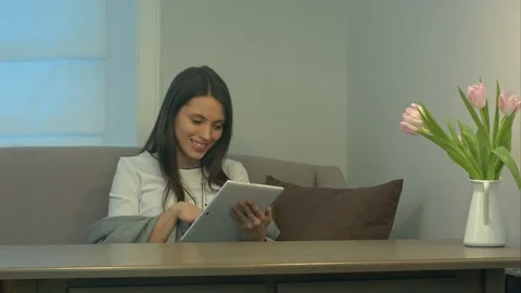 Attractive girl sitting on sofa using touchpad and smiling Vídeo Stock 73463175
