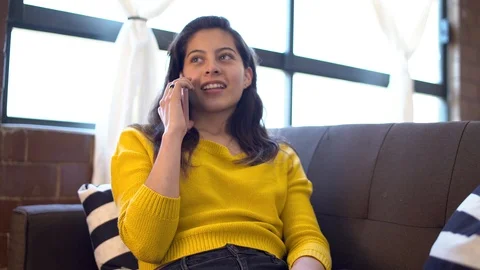 Attractive girl sitting on a sofa while talking on the phone Video stock 126254366