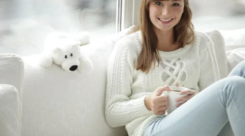Attractive girl sitting by window drinking tea looking at camera and smiling Stock Footage 34150208
