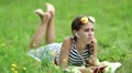 Attractive girl in sunglasses with red smartphone lies on the grass HD Footage