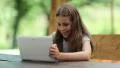 Attractive girl with tablet computer sits at the table in summerhouse HD Footage