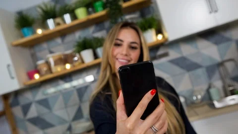 Attractive girl uses her phone in a kitchen. Stock Footage