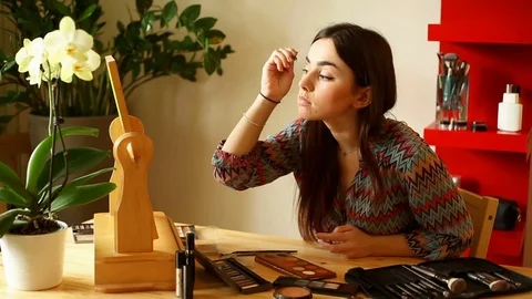 Attractive girl using shadow while painting her eyebrows Stock Footage 73683542