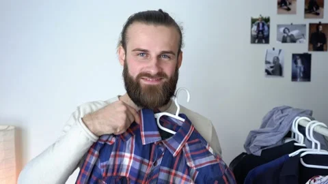 Attractive guy is looking into the mirror Putting together outfit with new shirt Stock Footage 147898103
