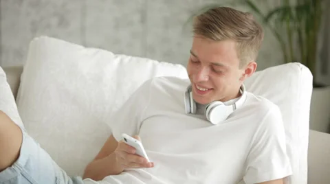 Attractive guy relaxing on sofa using cellphone and eating apple Video stock 27692029