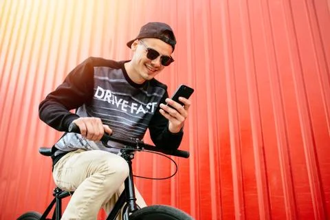 Attractive guy sitting using a cell phone while sitting on bike. Stock Photos
